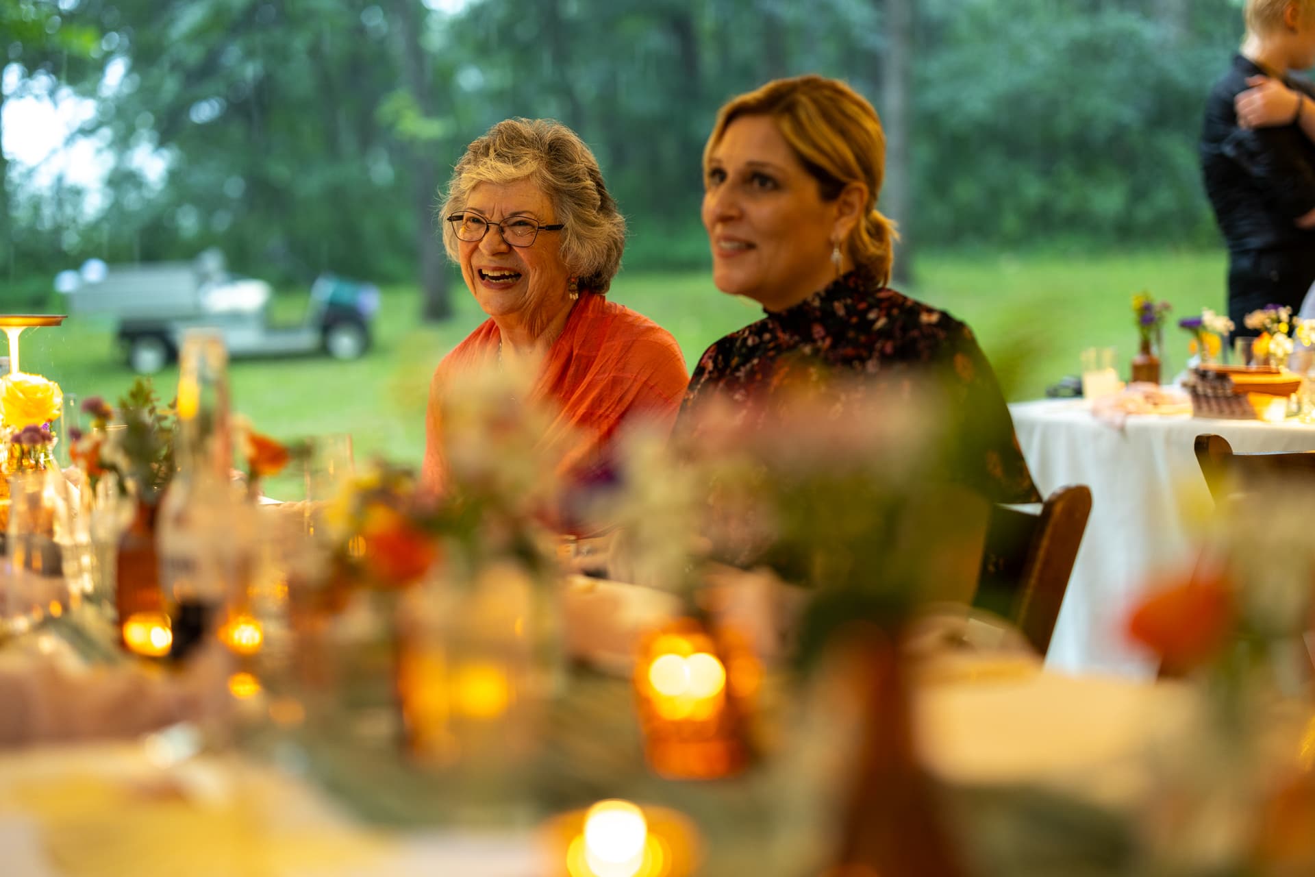 Two women laugh at a wedding reception.